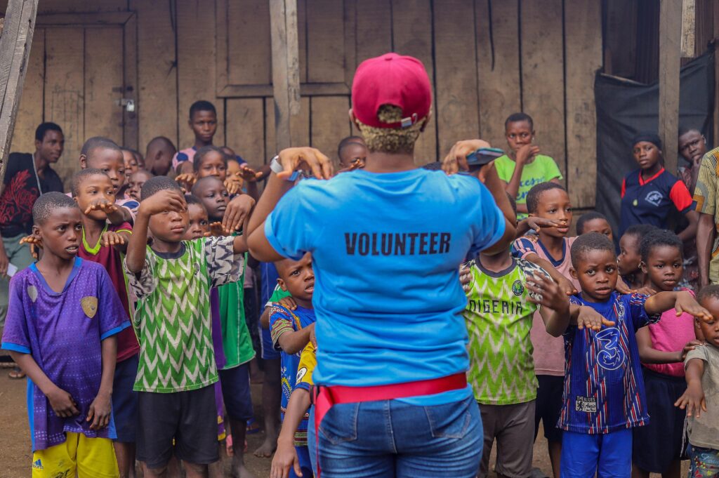 pexels photo 9090746 9090746 A volunteer guides a diverse group of children in an outdoor activity, fostering community spirit and teamwork.
